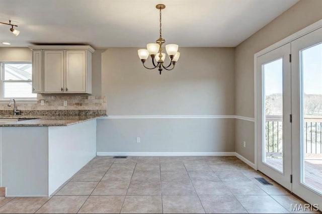 911 Valse Ct, Lake St Louis, MO 63367 - kitchen with tasteful backsplash, a chandelier, light stone counters, light tile patterned flooring, and decorative light fixtures