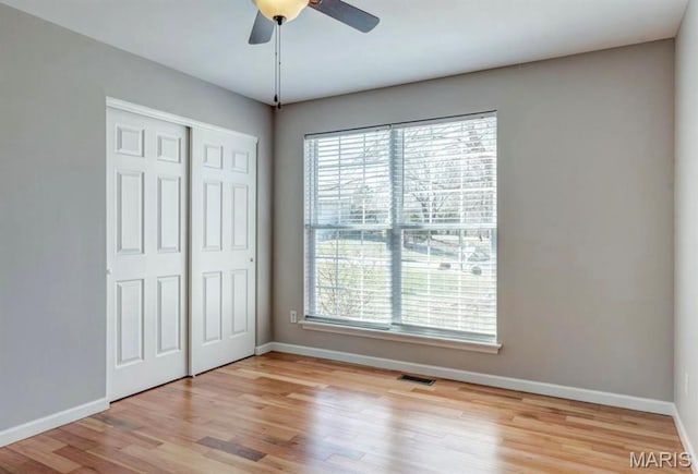 911 Valse Ct, Lake St Louis, MO 63367 - unfurnished bedroom with multiple windows, baseboards, and light wood-style floors