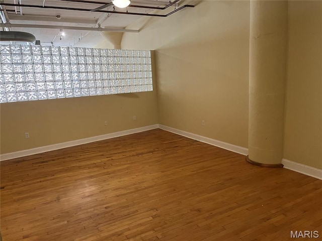 spare room featuring baseboards and wood finished floors