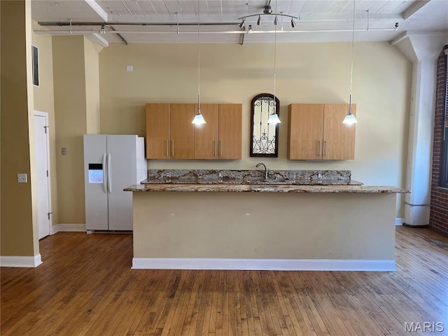 kitchen featuring white refrigerator with ice dispenser, a high ceiling, an island with sink, a sink, and dark wood-style flooring