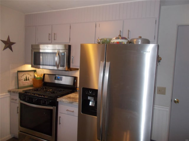 kitchen with stainless steel appliances, white cabinets, and backsplash