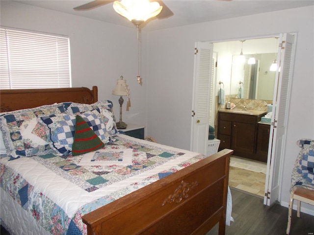 bedroom with dark wood finished floors, a sink, ensuite bath, and ceiling fan