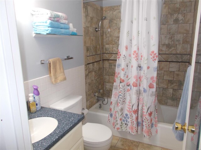 bathroom featuring tile walls, shower / bath combo with shower curtain, vanity, and toilet