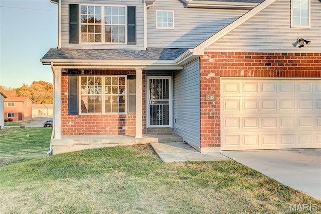 doorway to property with brick siding, a yard, driveway, a garage, and roof with shingles