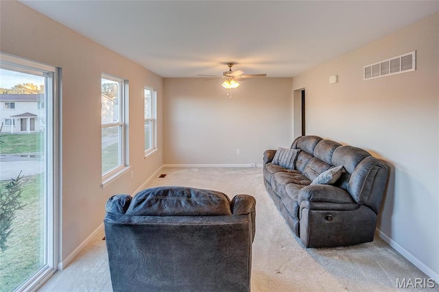 living room featuring light colored carpet, ceiling fan, and baseboards