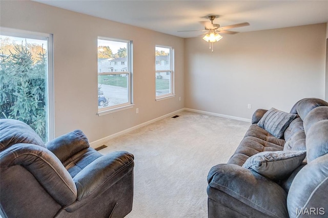 carpeted living area featuring baseboards and ceiling fan