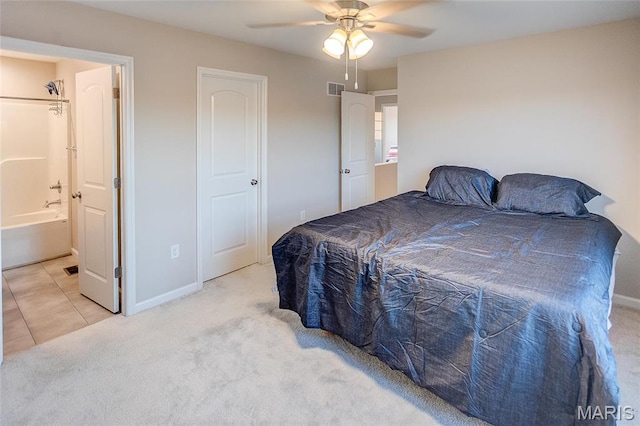 carpeted bedroom with baseboards, ensuite bath, ceiling fan, and tile patterned floors