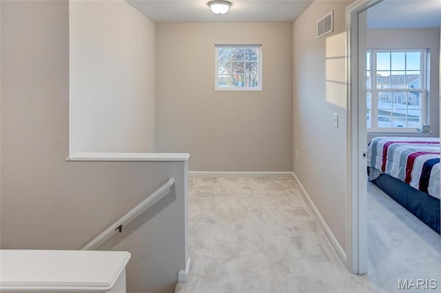 corridor with an upstairs landing, carpet flooring, and baseboards