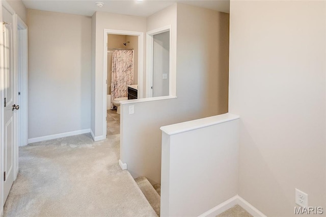 corridor featuring light carpet and baseboards