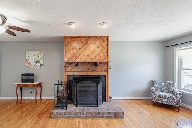 890 Tyson Dr, Florissant, MO 63031 - living room with wood finished floors, a ceiling fan, baseboards, a fireplace with raised hearth, and a textured ceiling
