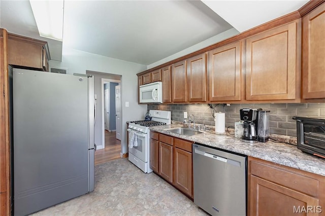 890 Tyson Dr, Florissant, MO 63031 - kitchen featuring stainless steel appliances, a sink, backsplash, and brown cabinetry