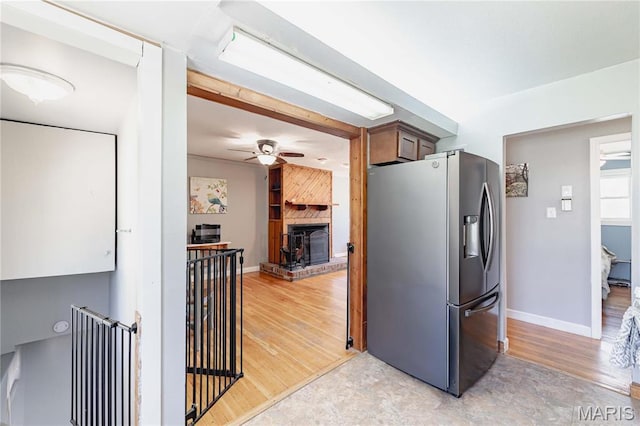 890 Tyson Dr, Florissant, MO 63031 - kitchen with stainless steel fridge with ice dispenser, a ceiling fan, a large fireplace, baseboards, and light wood-type flooring