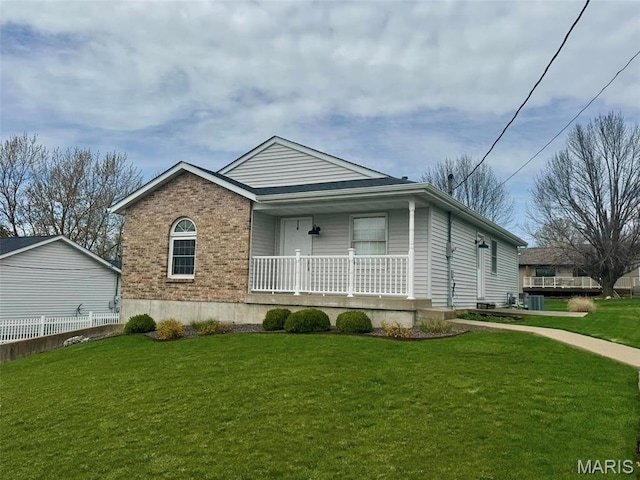 ranch-style home with covered porch, a front yard, brick siding, and central air condition unit
