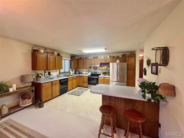 kitchen featuring stainless steel appliances, a peninsula, a textured ceiling, light countertops, and a breakfast bar area