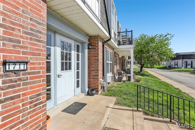 property entrance with a balcony and brick siding