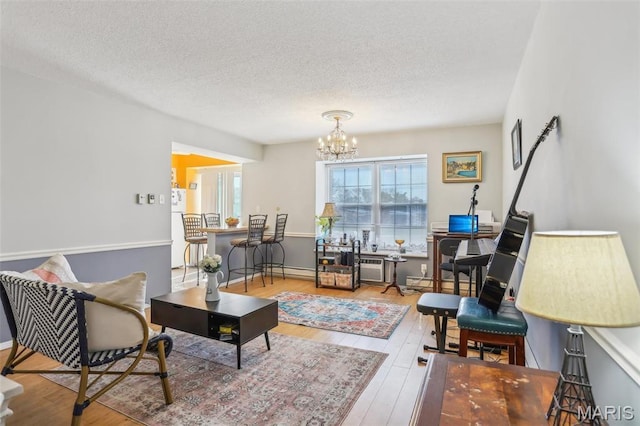 living room featuring a chandelier, a textured ceiling, wood finished floors, and a baseboard heating unit