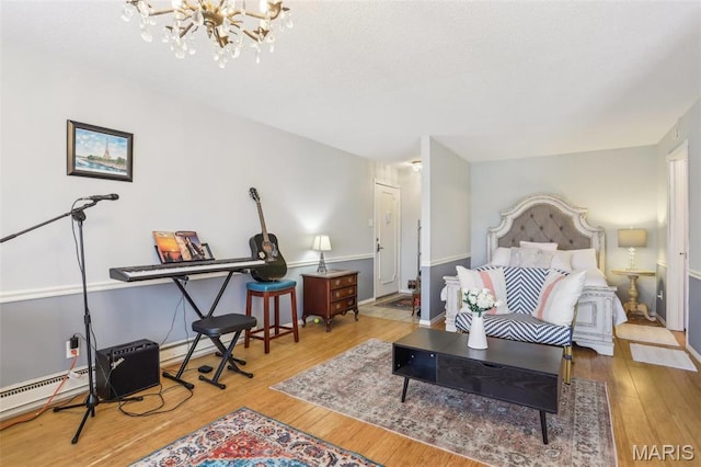 bedroom with wood finished floors, a chandelier, baseboard heating, and baseboards