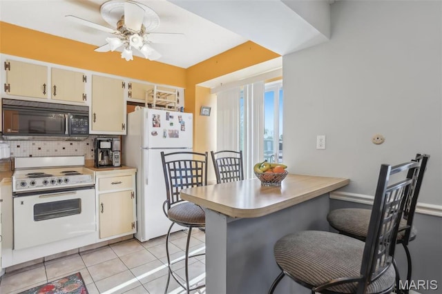 kitchen with white appliances, backsplash, a breakfast bar area, and ceiling fan