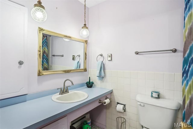 bathroom with vanity, toilet, and tile walls