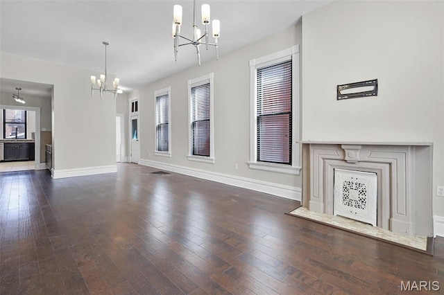 2835 Shenandoah Ave, Saint Louis, MO 63104 - unfurnished living room featuring a chandelier, baseboards, and hardwood / wood-style floors