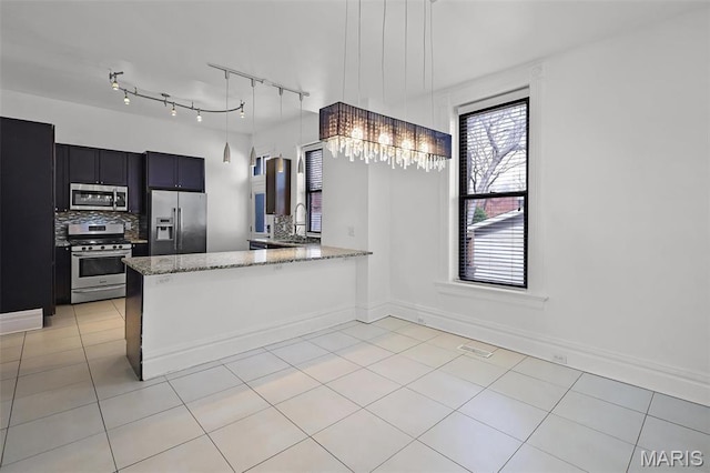 2835 Shenandoah Ave, Saint Louis, MO 63104 - kitchen featuring stainless steel appliances, light stone counters, tasteful backsplash, light tile patterned floors, and a peninsula