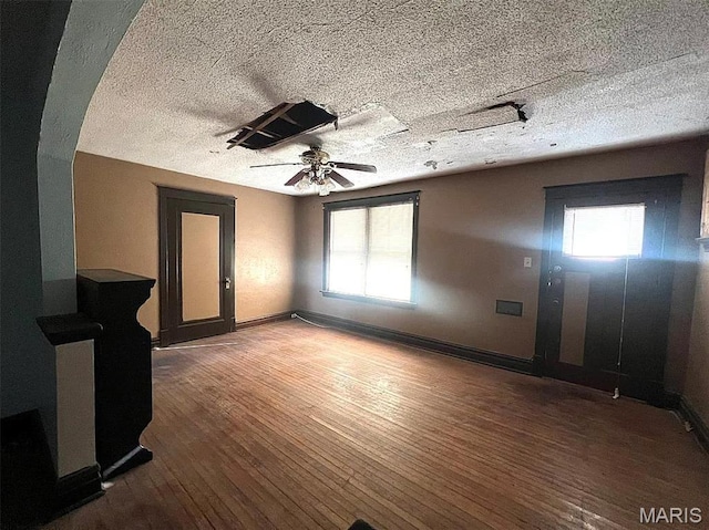 4873 Kossuth Ave, Saint Louis, MO 63115 - unfurnished living room with a textured ceiling, hardwood / wood-style floors, plenty of natural light, a ceiling fan, and baseboards