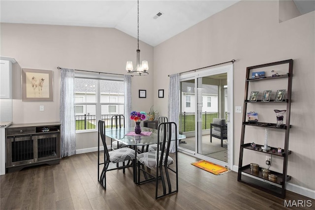 dining area with a chandelier, dark wood finished floors, baseboards, and high vaulted ceiling