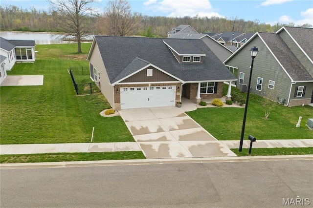 view of front of property with brick siding, a water view, a garage, a front yard, and driveway