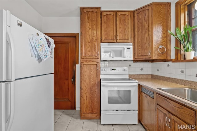 3981 Canterbury Dr, Saint Louis, MO 63121 - kitchen with white appliances, brown cabinets, light tile patterned floors, a sink, and tasteful backsplash