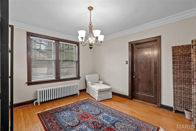 3981 Canterbury Dr, Saint Louis, MO 63121 - living area with radiator heating unit, a chandelier, crown molding, wood finished floors, and baseboards