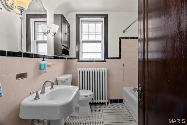 3981 Canterbury Dr, Saint Louis, MO 63121 - bathroom featuring radiator heating unit, tile walls, a wainscoted wall, toilet, and a sink
