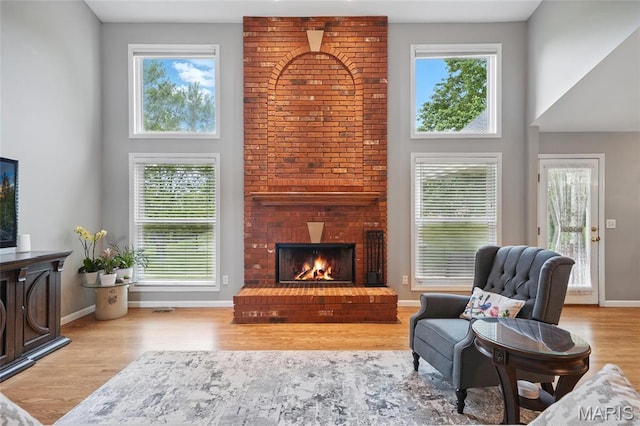 13456 Sunset Meadows Ln, Saint Louis, MO 63128 - living room featuring wood finished floors, a towering ceiling, baseboards, and a fireplace