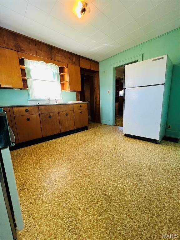 604 Salling St, Perry, MO 63462 - kitchen featuring freestanding refrigerator, open shelves, wood walls, brown cabinetry, and range