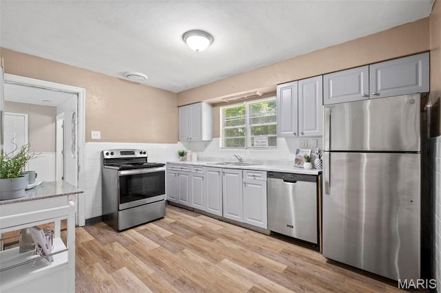 309 N Schlueter Ave, Saint Louis, MO 63135 - kitchen with appliances with stainless steel finishes, light countertops, light wood-style flooring, tile walls, and wainscoting