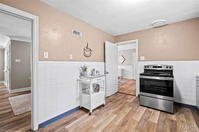 309 N Schlueter Ave, Saint Louis, MO 63135 - kitchen with stainless steel range with electric cooktop, tile walls, light wood-style floors, and a wainscoted wall