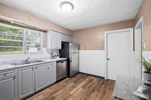 309 N Schlueter Ave, Saint Louis, MO 63135 - kitchen featuring appliances with stainless steel finishes, tile walls, light countertops, wood finished floors, and a wainscoted wall