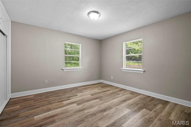 309 N Schlueter Ave, Saint Louis, MO 63135 - unfurnished bedroom featuring multiple windows, wood finished floors, and a closet
