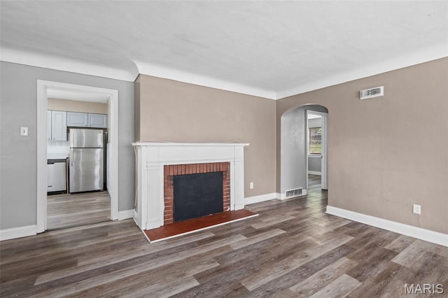 309 N Schlueter Ave, Saint Louis, MO 63135 - unfurnished living room featuring arched walkways, wood finished floors, and a brick fireplace