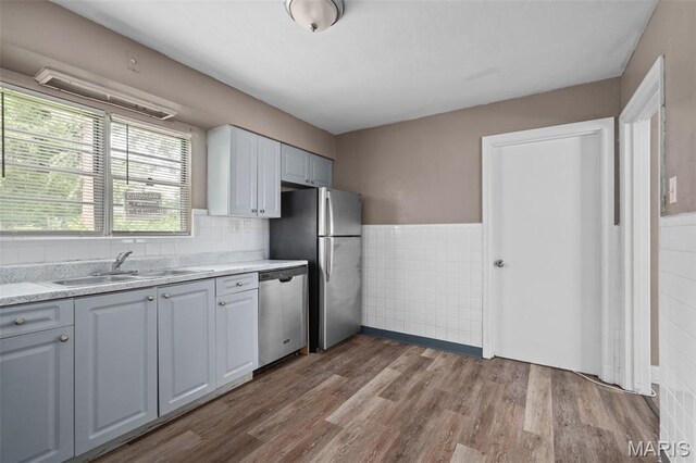 309 N Schlueter Ave, Saint Louis, MO 63135 - kitchen with appliances with stainless steel finishes, tile walls, light countertops, wood finished floors, and wainscoting