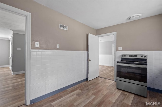 309 N Schlueter Ave, Saint Louis, MO 63135 - kitchen with stainless steel range with electric stovetop, light wood-style flooring, a wainscoted wall, and tile walls