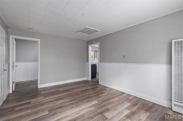309 N Schlueter Ave, Saint Louis, MO 63135 - spare room featuring a heating unit, wood finished floors, attic access, and wainscoting
