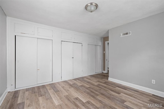 309 N Schlueter Ave, Saint Louis, MO 63135 - unfurnished bedroom with multiple closets and light wood finished floors