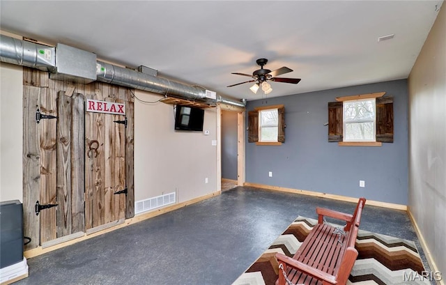 basement with ceiling fan and baseboards