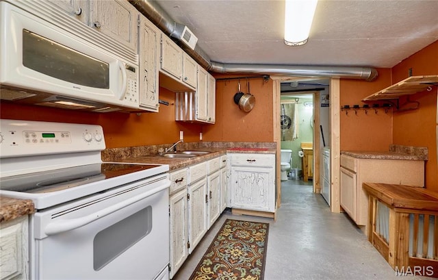 kitchen with white appliances, finished concrete flooring, a sink, and white cabinetry