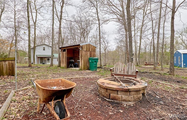 view of yard with a fire pit, a storage unit, and an outdoor structure