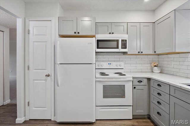 2014 Greenglen Dr Unit 101, Saint Louis, MO 63122 - kitchen featuring white appliances, gray cabinetry, wood finished floors, decorative backsplash, and light stone countertops