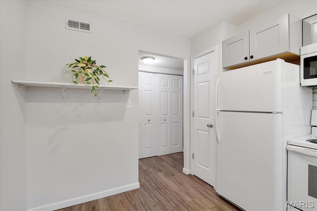 2014 Greenglen Dr Unit 101, Saint Louis, MO 63122 - kitchen featuring white appliances, wood finished floors, baseboards, and light countertops