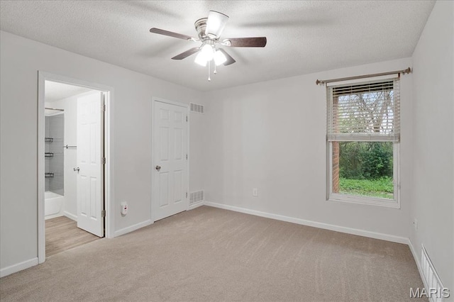 2014 Greenglen Dr Unit 101, Saint Louis, MO 63122 - unfurnished bedroom with carpet, a textured ceiling, baseboards, ensuite bathroom, and a ceiling fan