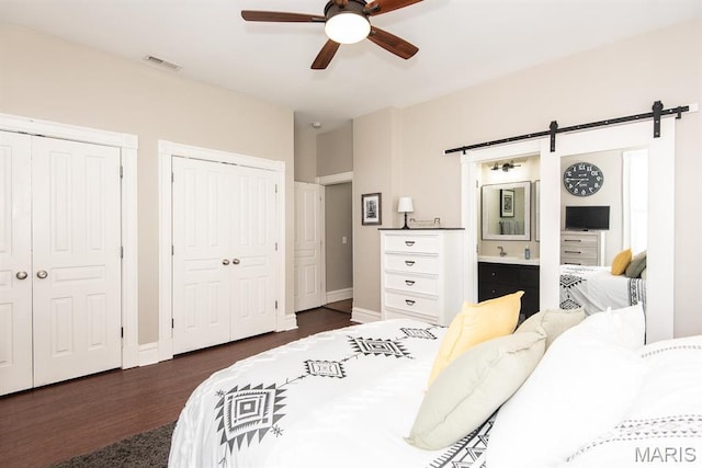 2712 Potomac St, Saint Louis, MO 63118 - bedroom featuring a barn door, two closets, dark wood finished floors, ceiling fan, and baseboards