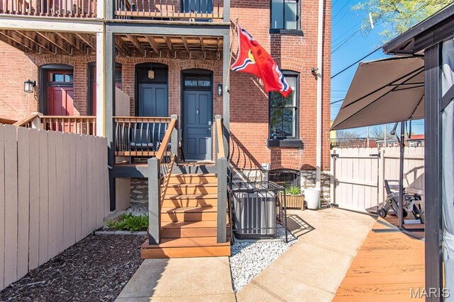 2712 Potomac St, Saint Louis, MO 63118 - view of exterior entry featuring brick siding, fence, covered porch, and cooling unit